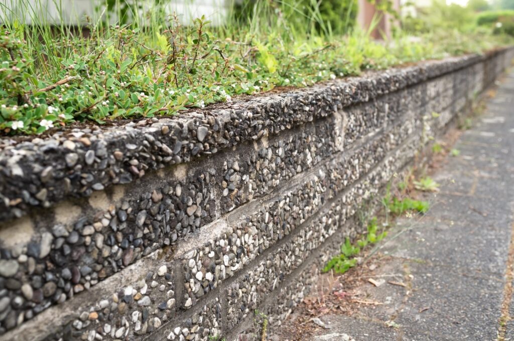 Old beautiful fence made of small stones and concrete on the street of a provincial town.